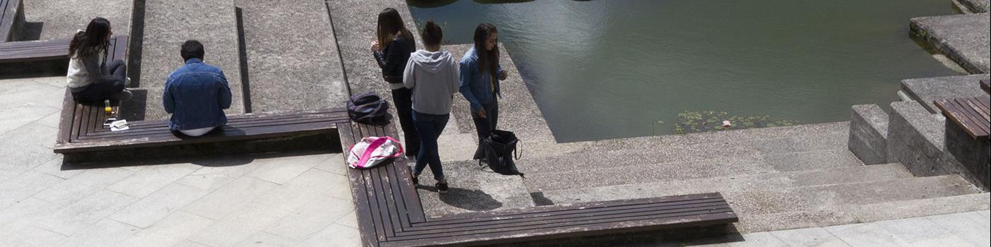 Varios alumnos e alumnas diante dun estanque nun dos campus